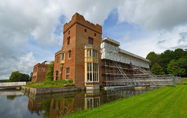 Oxburgh Hall under going roof repairs with scaffolding  and moat. - obrazy, fototapety, plakaty