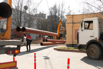 Laying heating pipes with a crane. Construction work in the city. Installation of underground water supply and sewerage. Cold and hot water, heating system of apartments in the house.
