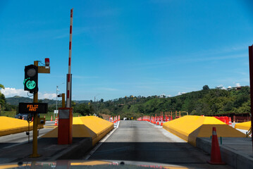 Automatic gate barrier open for vehicular passage at a Colombian highway toll.