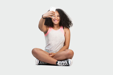 giovane ragazza isolata su sfondo bianco utilizza il telefono cellulare mentre è seduto
