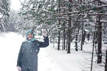 A happy woman in a winter snow-covered forest