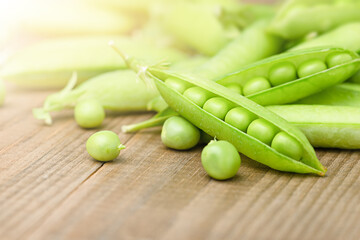 heap of fresh pea pods on a wooden table
