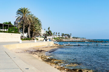 Sandy and rocky beach. Paphos, Cyprus. Green palms and warm sea.