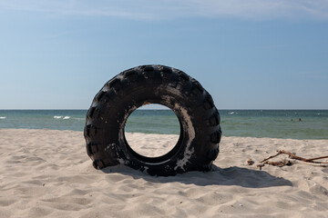 Big tyre on the beach, threat to environments. Contamination of the oceans by litter