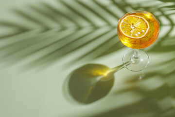 summer refreshing cocktail on a light green background with a shadow from a palm tree, top view