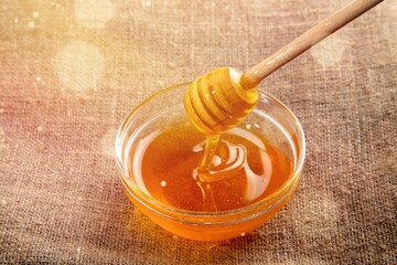 Golden honey flows from the stick and a jar. Aromatic nectar