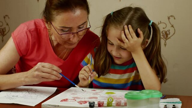 A grown woman teaches a little girl the art of drawing.