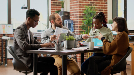 Multiethnic team of people working on business collaboration, brainstomring ideas to plan research presentation. Meeting in boardroom to do teamwork on report project. Tripod shot.