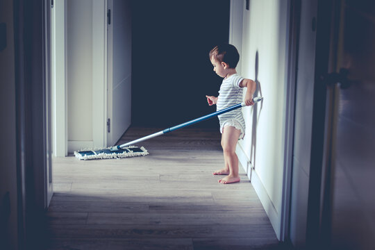 Ni&ntilde;o beb&eacute; limpiando la casa, pasando la mopa por el pasillo