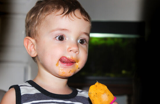 Menino saboreando um picol&eacute; de fruta natural