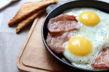 Tasty fried eggs with bacon on table, closeup. Space for text