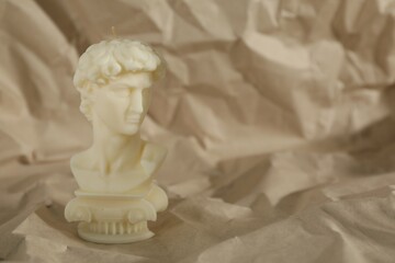 Beautiful David bust candle on crumpled paper. Space for text