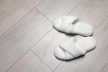 Fototapeta na wymiar Pair of soft slippers on wooden floor, above view. Space for text