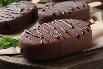 Delicious glazed ice cream bars and mint on wooden board, closeup