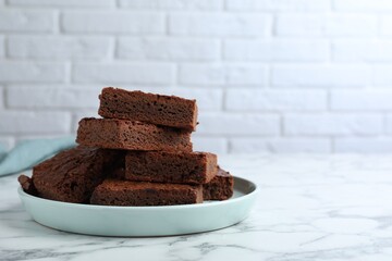 Delicious chocolate brownies on white marble table. Space for text