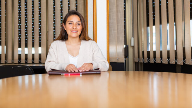 Positive young adult businesswoman working at meeting room in office
