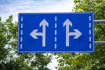 Two Way Road Sign with blue sky and trees