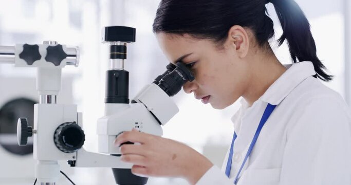 Medical science intern using a microscope for a futuristic, innovative cure. Smart young scientist trainee busy doing development research in a laboratory to find new disease data