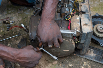 An Engineer working on a small electricity generator in an engineering workshop, undergoing repair and maintenance for better generation of electrical energy for household and business in Nigeria