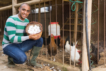 Portrait of positive man farmer with a basket of chicken eggs © JackF