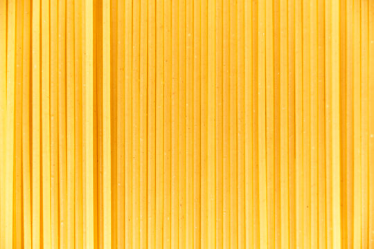 Italian food background, macro image of raw spaghetti filling the frame in a textured design of vertical pasta lines.