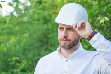 Man builder wearing hardhat outdoors natural background, copy space