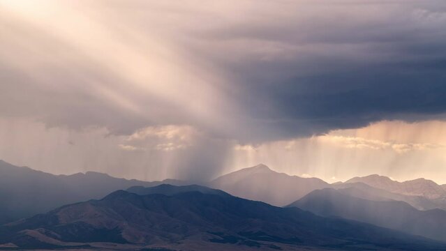Timelapse of rain storm moving over mountain tops in Utah as sun rays shine through the clouds.