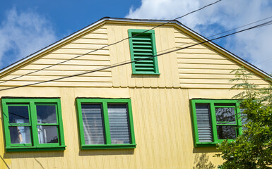 Fototapeta na wymiar Old Yellow and Green House Under Blue Sky.