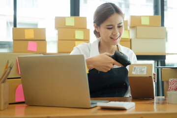 Young asian businesswoman use bar code scanner Scan the barcode on the product box.