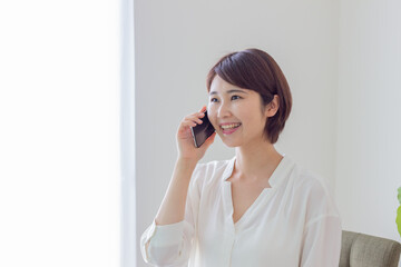 スマホで電話をする笑顔の女性　（スマホ・電話・通話）