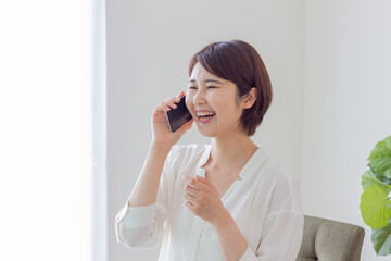 スマホで電話をする笑顔の女性　（スマホ・電話・通話）