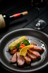 Juicy duck breast steak with caramelized fruit and orange sauce on a dark wooden floor