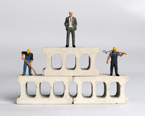 Miniature people standing on miniature bricks. The concept of social inequality.
