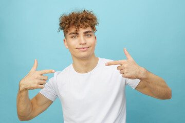 Portrait of a man in a casual white T-shirt, holding his hands in a gesture, emotionally smiling pointing at himself. a closed studio shot isolated on a blue background
