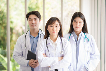 Group of Asian doctors team portrait standing with colleagues in background.