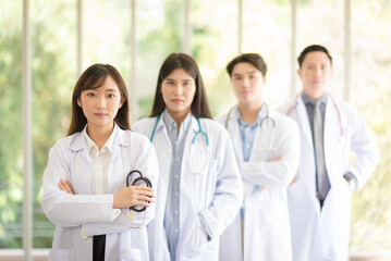 Group of Asian doctors team portrait in white lab coat professional uniform standing with colleagues in background.