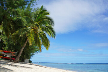 Coconut palm trees, a beautiful white sand beach and a tropical lagoon on a Pacific Island.
