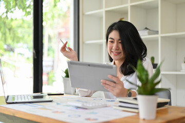 Asian businesswoman planning her financial investment strategy on a digital tablet.