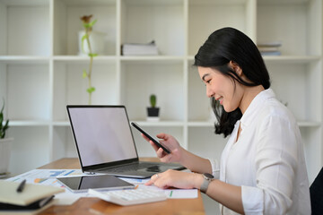 Beautiful Asian businesswoman working at her office desk, analysing business report.