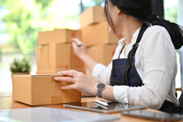 Asian female e-commerce startup preparing her shipping packages in the office.