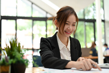 Asian businesswoman sits in the office co-working space working on her financial report.