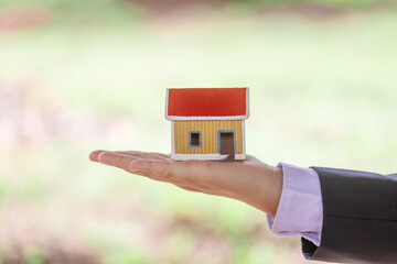 Business man hand holding home model. Property investment and insurance concept.