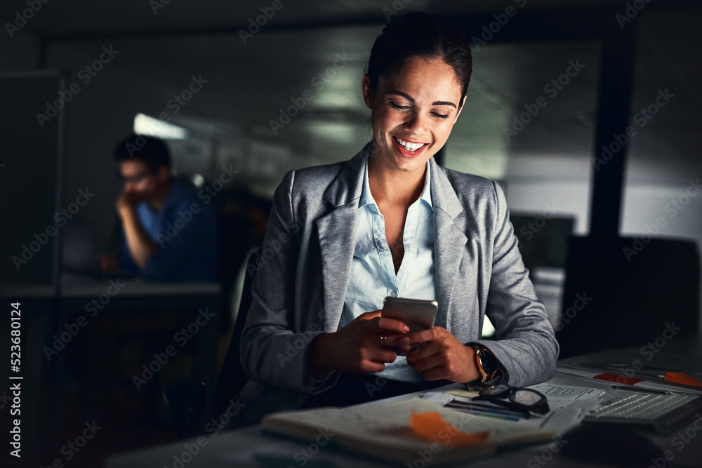 Poster Woman reading text late on phone, smiling at a message and looking at social media posts online while working in a dark office at night. Happy corporate worker checking emails and doing overtime