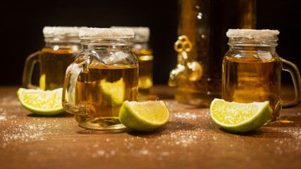 tequila shots served in jars with salt and lime on wooden table