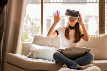 girl sitting on the sofa wearing virtual reality glasses Look at the website online and use the hand-animated 3D simulated screen, future technology concept.