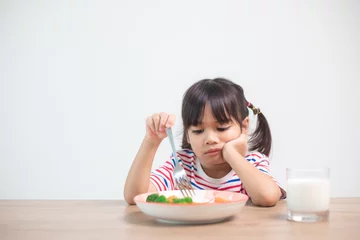 Zelfklevend Fotobehang Nutrition & healthy eating habits for kids concept. Children do not like to eat vegetables. Little cute girl refuses to eat healthy vegetables. © FAMILY STOCK