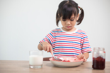 Asian girl having breakfast with bread and jam with a glass of milk