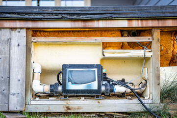 Side of hot tub with panel removed to repair and complete maintenance on the recirculation pump.