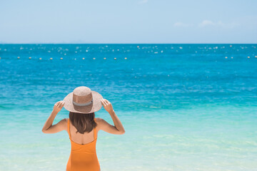 Woman tourist in orange swimsuit and hat, happy traveler sunbathing at Paradise beach on Islands....