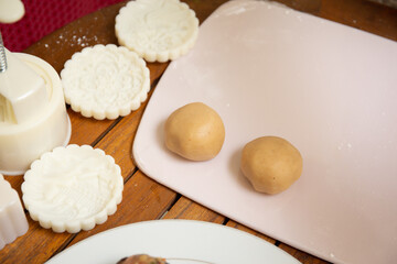 Female hands making dough for mooncake, homemade cantonese moon cake pastry on baking tray before baking for traditional festival. Travel, holiday, food concept